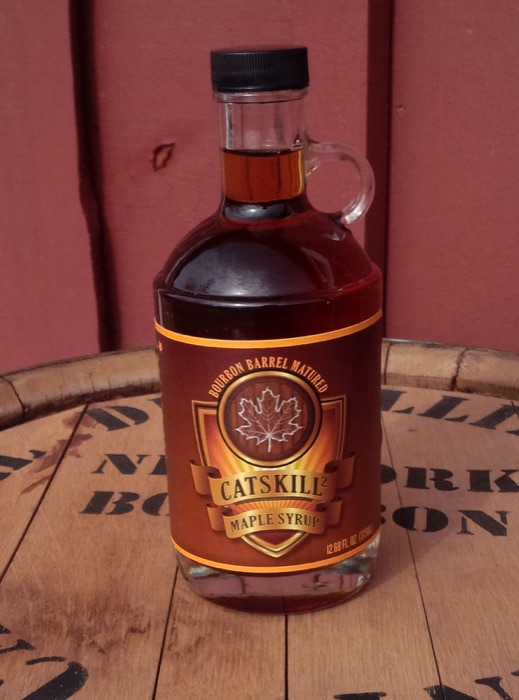 Bottle of bourbon barrel matured maple syrup on a whiskey barrel